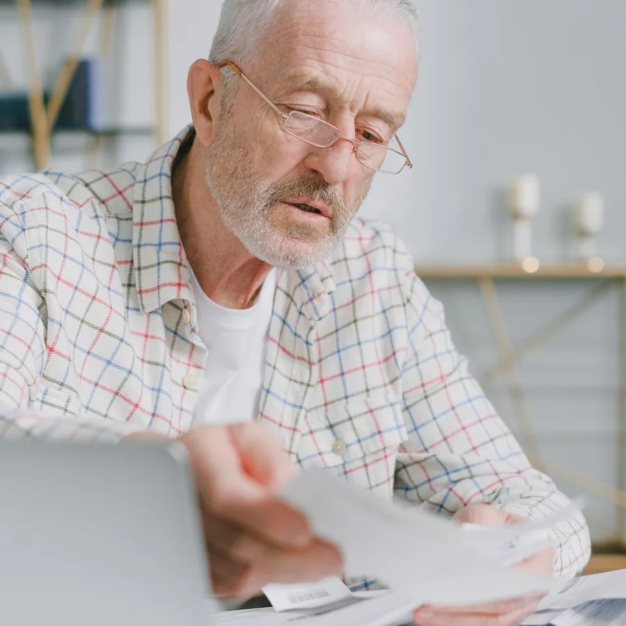Senhor de óculos conferindo documentos e contas em casa